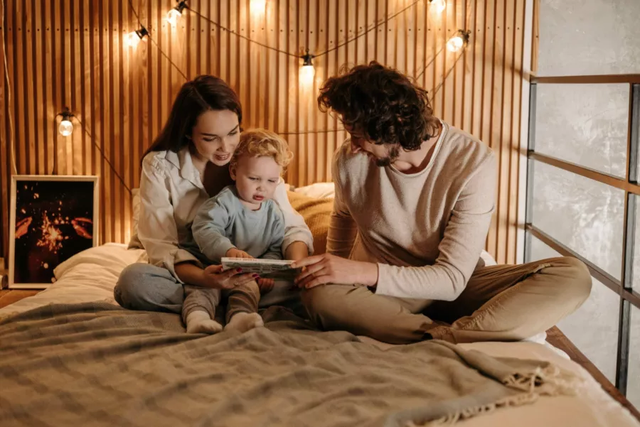 Young couple and baby reading on bed